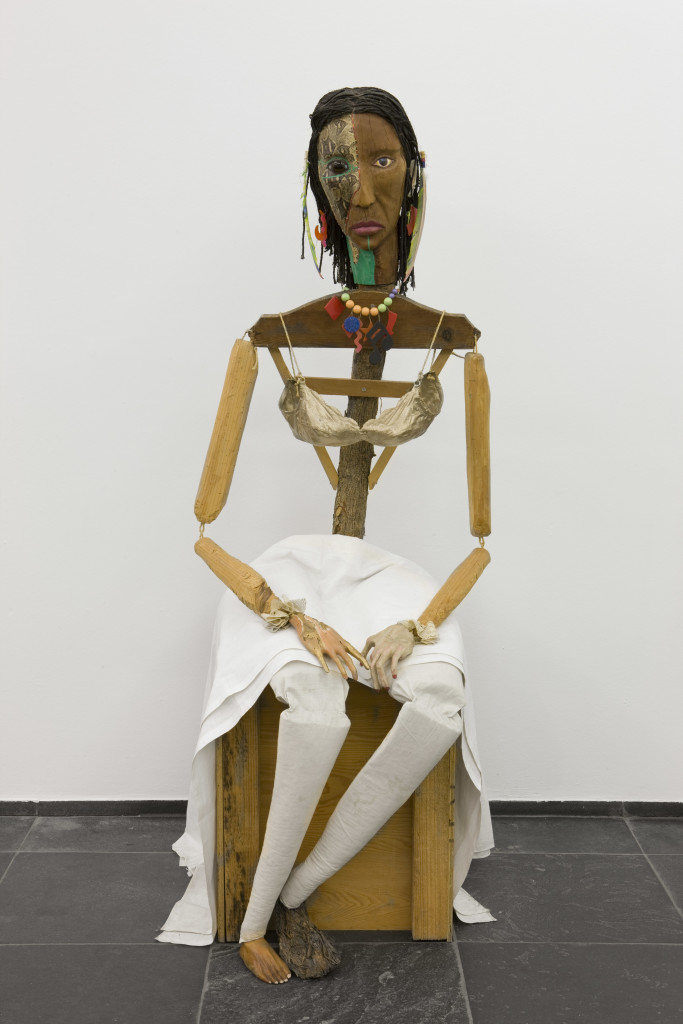 Jimmie Durham, Malinche, 1988-1992. Guava, pine branches, oak, snakeskin, polyester bra soaked in acrylic resin and painted gold, watercolor, cactus leaf, canvas, cotton cloth, metal, rope, feathers, plastic jewelry, glass eye. 70 × 23 ⅝ × 35 in. (177 × 60 × 89 cm). Stedelijk Museum voor Actuele Kunst (SMAK), Ghent, Belgium. Image ©S.M.A.K. / Dirk Pauwels. 